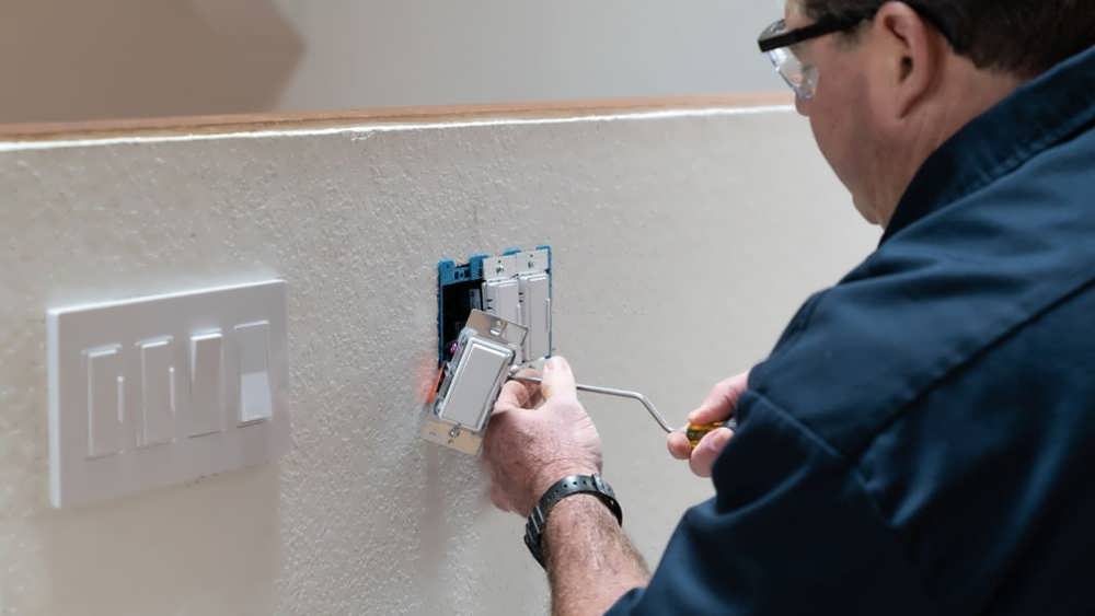 مرد برق کار در حال نصب کلید دیمر دار به روی دیوار